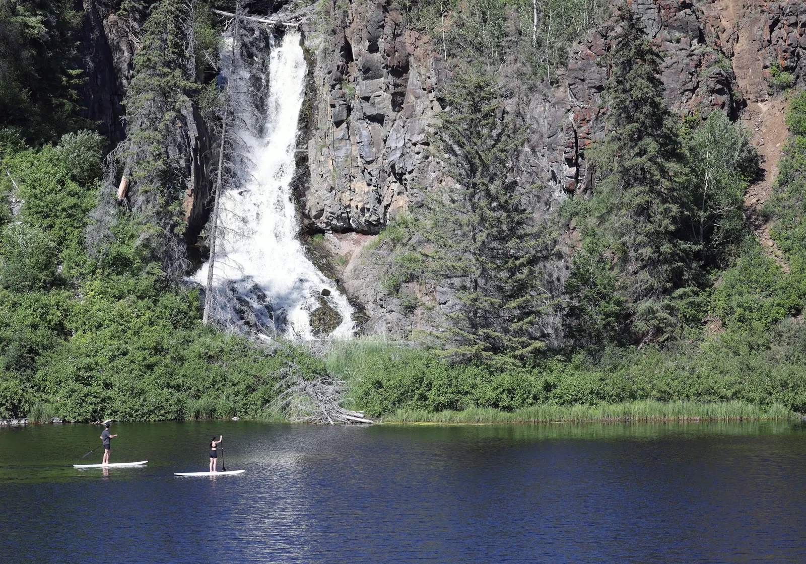 paddle boarders next to a waterfall at Siwash Lake